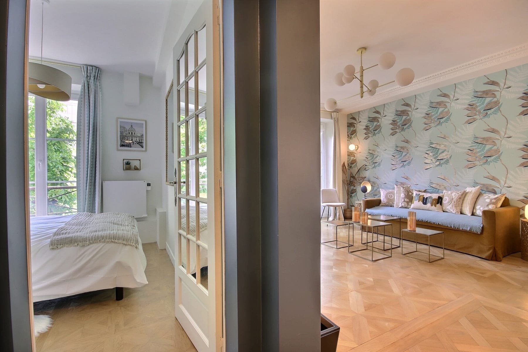 Chambre vue depuis le séjour à travers une porte vitrée, papier peint végétal et parquet en point de Hongrie