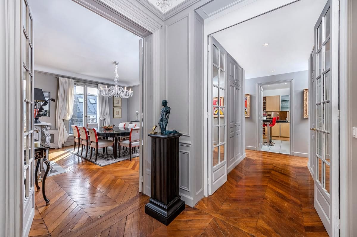 Entrée en enfilade sur la salle à manger et la cuisine, portes vitrées et parquet à chevrons