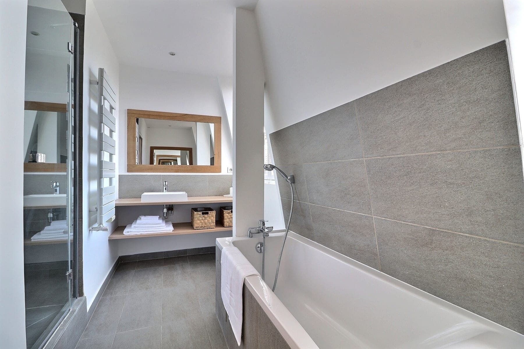 Salle de bains mansardée avec baignoire et vasque, photographiée sans déformer l’espace