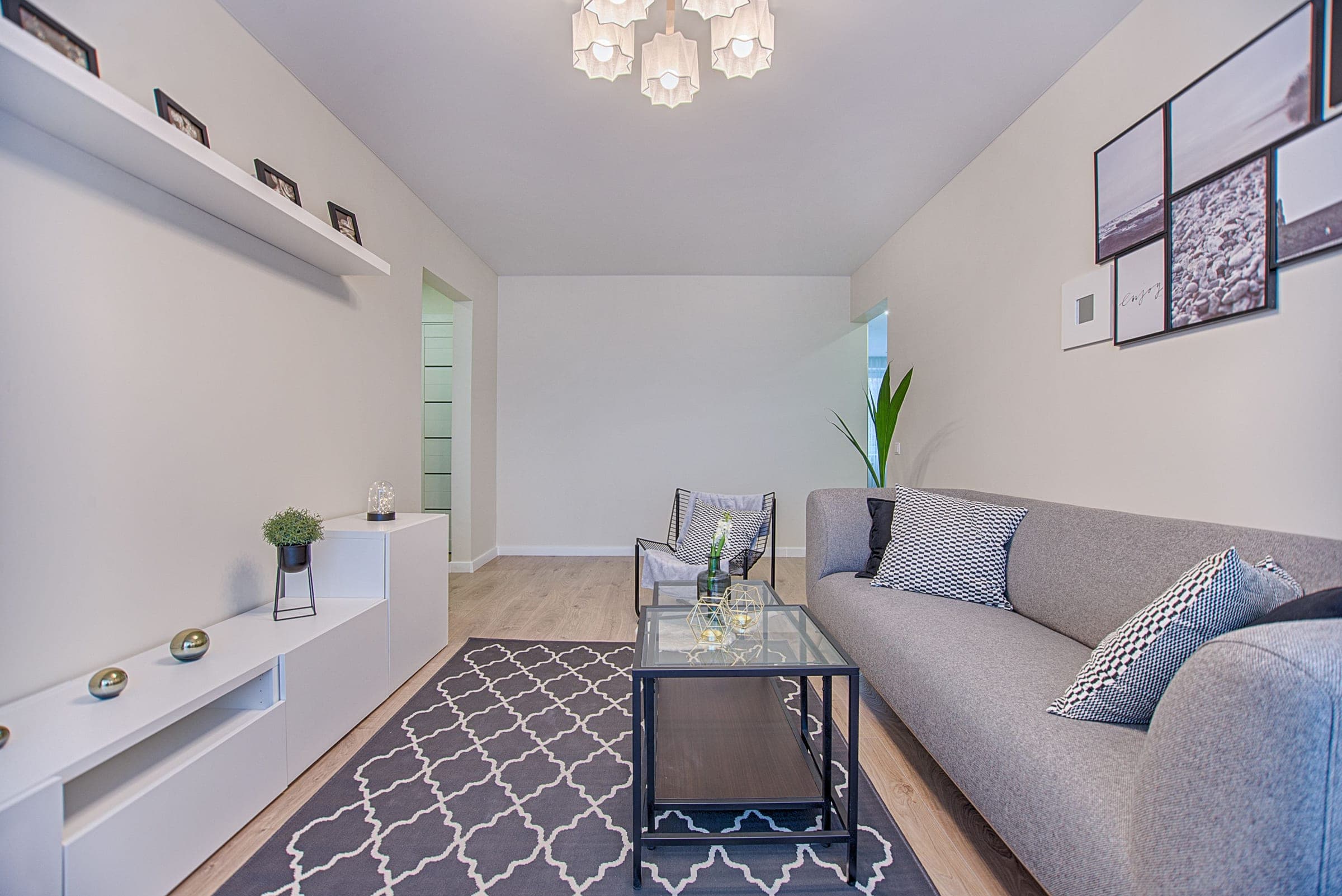 Séjour compact avec canapé gris, niches murales et tapis graphique