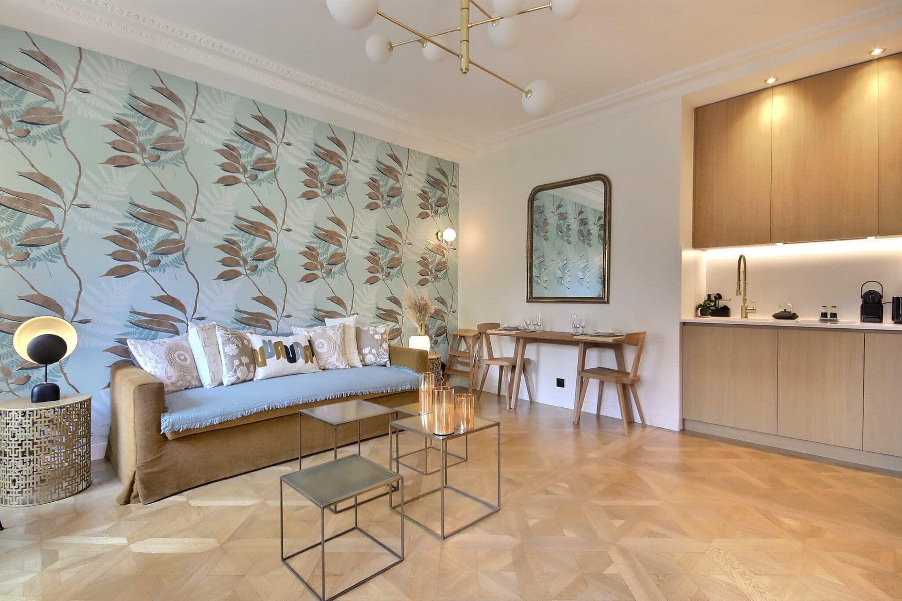 Séjour avec kitchenette, papier peint végétal et parquet de Versailles dans un appartement parisien