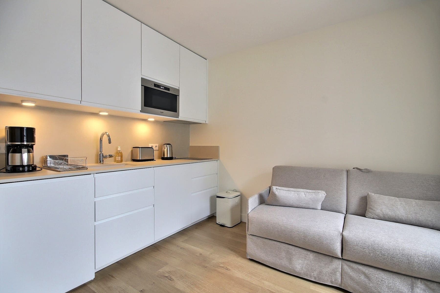 Studio parisien meublé : kitchenette et canapé-lit cadrés dans un seul volume